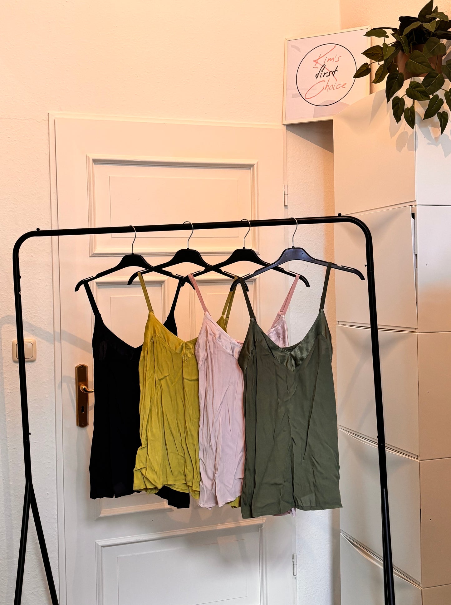 Viskose Trägertop in Schwarz, Olivgrün, Rosa und Khaki auf einem Kleiderständer